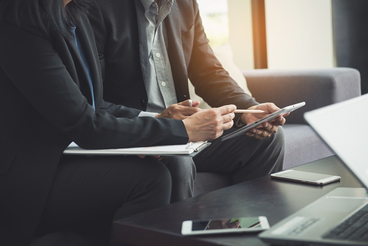 pessoas vestidas de modo formal analisando informações em um tablet