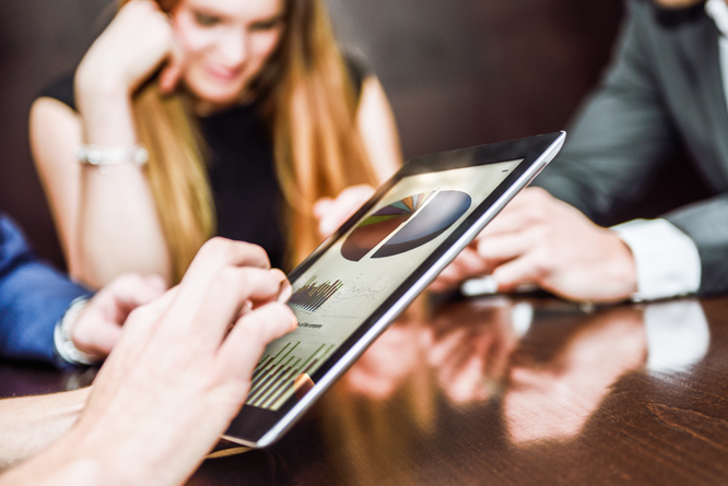 Pessoas lendo gráficos em uma reunião através de um tablet