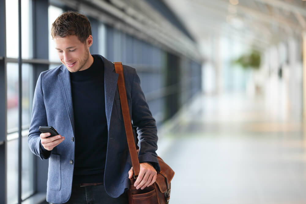 Homem de terno usando celular enquanto caminha