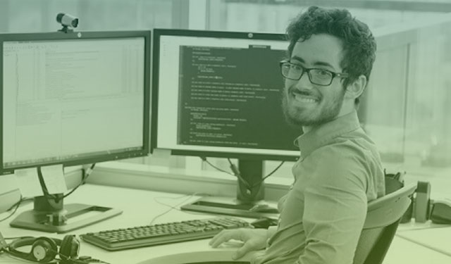 Pessoa utilziando computador exibindo códigos olhando para a tela sorrindo