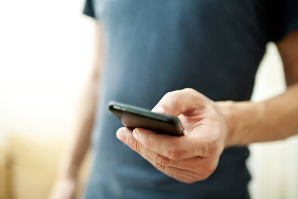 Homem com roupa casual utilizando o celular