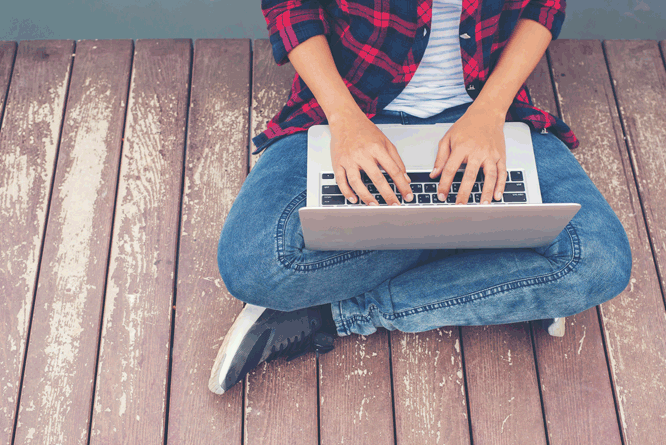 Pessoa sentada em um deck programando em um laptop