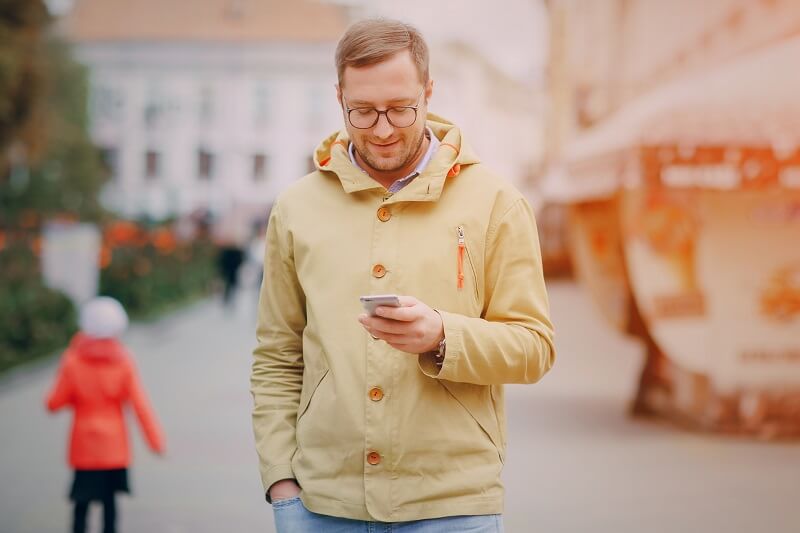 Homem utilizando celular enquanto caminha
