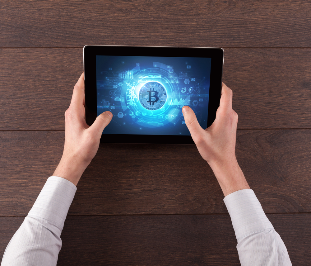 Homem segurando tablet mostrando imagem do Bitcoin