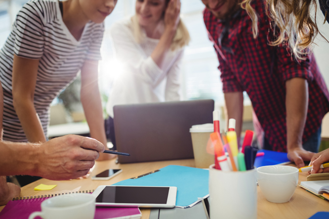 Pessoas em uma mesa de reunião olhando para a tela de um computador