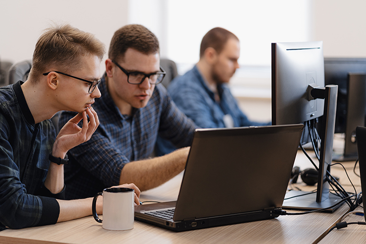 Homens analisando requisitos em uma tela de computador