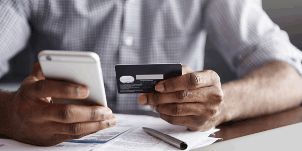 Pessoa digitando dados do cartão de crédito em loja online pelo celular