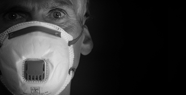 Imagem em preto e branco exibindo homem utilizando máscara de proteção
