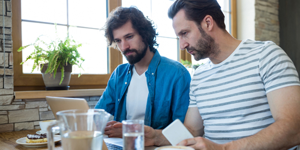 Homens em cafeteria utilizando computador