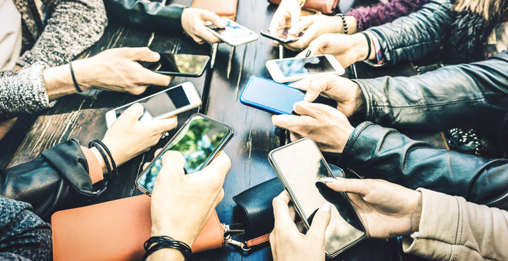 Pessoas colocando seus celulares em formatos de círculo numa mesa