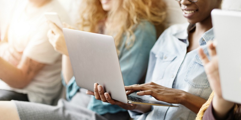 Pessoa utilizando computador com outras pessoas ao redor