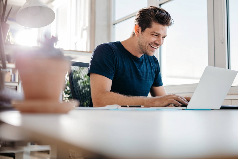 Homem sorrindo em mesa de escritório