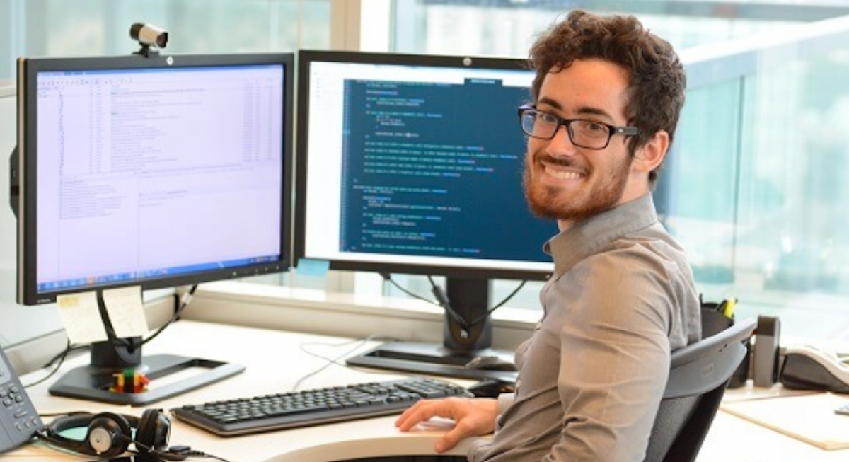 Homem sorrindo analisando dados em computador