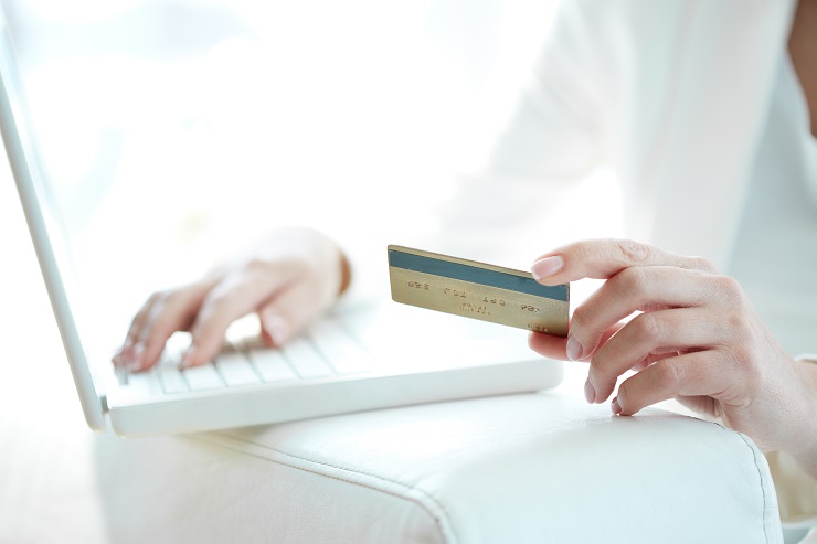 Mulher utilizando computador com cartão na mão