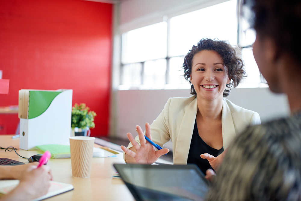 Mulher sorrindo conversando com colegas de trabalho