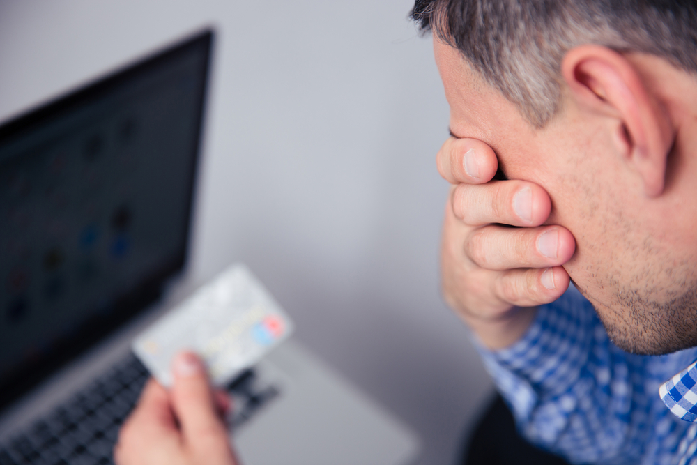 Homem chateado segurando cartão de crédito