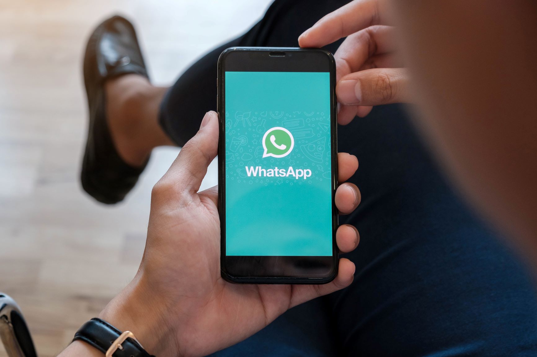 Homem segurando celular exibindo logo do WhatsApp