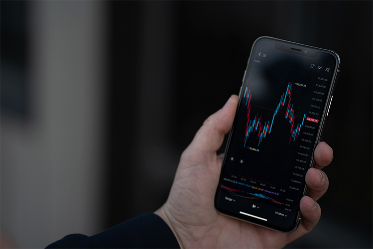 Investidor verificando dados do mercado de ações na bolsa por meio de um aplicativo móvel em um smartphone.